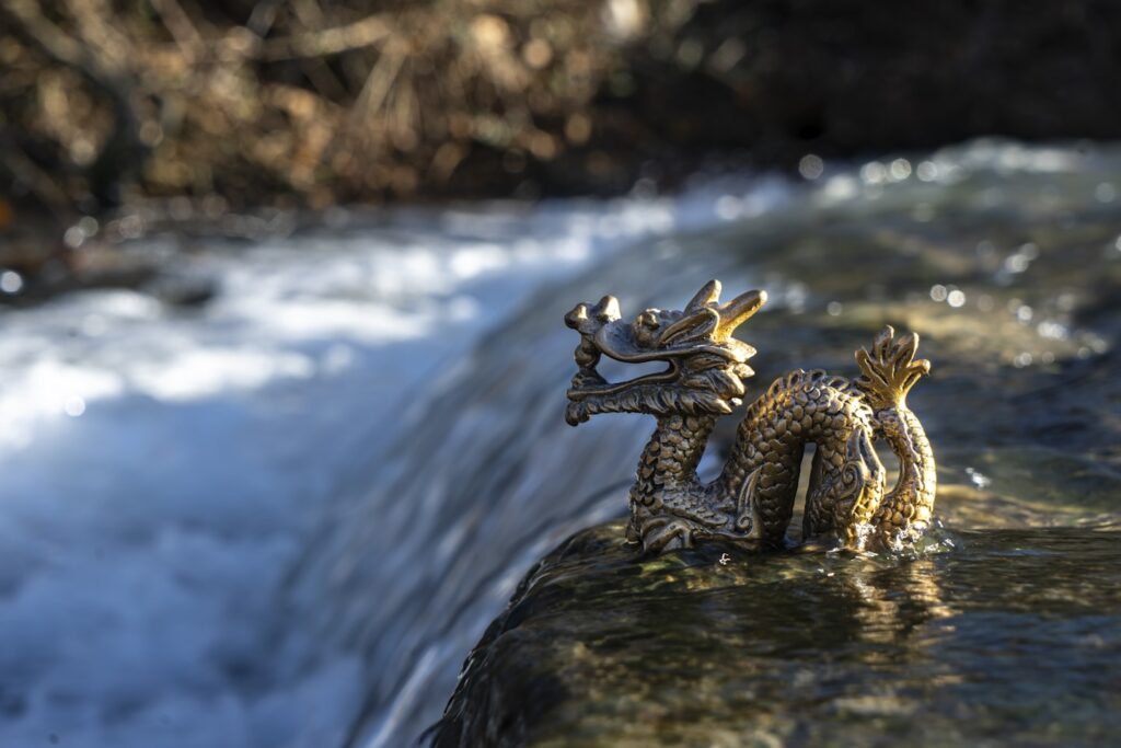 a Chinese Dragon Statue on the edge of a waterfall