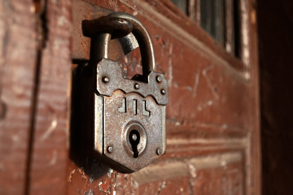 Vieux cadenas en fer forgé fermant une porte en bois patinée, ambiance d’escape game médiéval